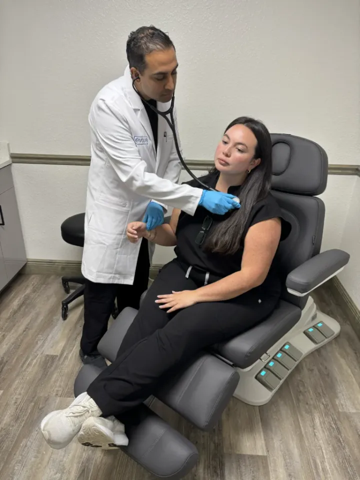 An Evolve Health physician examines a patient in a treatment chair at a clinic.